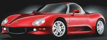 Obscure supercars of the 80's and 90's - Page 4 - General Gassing - PistonHeads - The image presents a sleek, red sports car with a distinctive design. Its body and wheels are in pristine condition, with a high gloss that reflects the surrounding light. The car is captured from a side angle, showing its long, low profile and the details of the wheels and tail lights. A reflection in the car's surface adds a sense of depth to the image. Overall, the car exudes an air of speed and elegance.