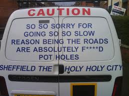 State Pistonheads Appalling Roads - The image depicts a white van, which serves as a mobile advertisement for a business. The side of the van features a sign that reads "Caution - Sorry for Going So Slow - Reason Being the Roads Are Absolutely F*cked - Sheffield Holy City", suggesting that the van is making its way through Sheffield and the driver is having to navigate through difficult road conditions. There is also text indicating that the van belongs to "Sheffield Holy Drain", which could be another indication of the challenges faced during transportation. The bold font of the text emphasizes the cautionary message intended to raise awareness about the circumstance.