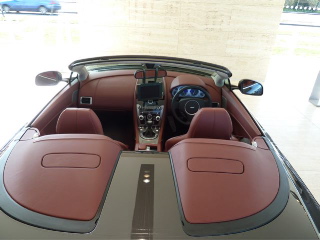 Owner Pistonheads Vantage - The image presents an interior view of a luxurious car dashboard. The car exhibits a sleek design, highlighted by cream interiors with red accents. The steering wheel and dashboard are neatly arranged in the center, ready for driving. The design and details indicate a high-end vehicle, possibly a luxury car. The seat appears plush and comfortable, suggesting a focus on passenger comfort.