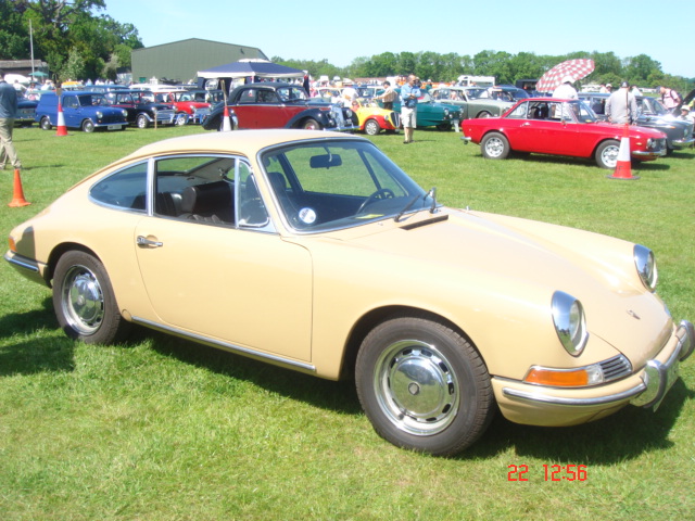 Old Warden car show - Page 1 - Classic Cars and Yesterday's Heroes - PistonHeads - This image captures a moment at a car show, where several vintage cars are on display in a grassy field. One of the vehicles, a yellow-cream Porsche 911, stands out prominently in the foreground. The car is facing the viewer with a set of people near it, suggesting the engaging atmosphere typical of such gatherings. The background reveals a line of more cars, suggesting that this car show boasts a diverse and impressive array of classic vehicles. The image is timestamped "23 12:56", possibly indicating the time when the photo was taken.