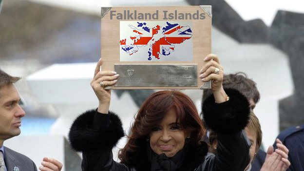 A woman is holding a sign that says <UNK> - Pistonheads - In the image, a woman is the central figure, standing amidst a crowd. She holds up a piece of paper, which is angled in such a way that it is partially obscured by her own face. The text on the paper is "Face Islands" written in bold letters. The background reveals a public, open-air space, with concrete structures and other people visible. The overall scene seems to depict a public event or gathering.