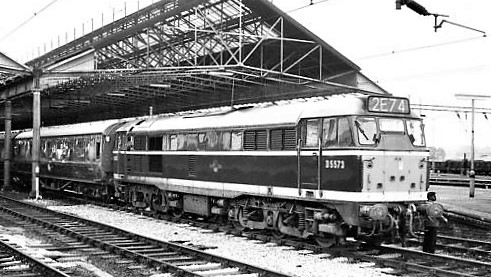 Loco sheds and other railway buildings.... - Page 5 - Boats, Planes & Trains - PistonHeads UK - The image showcases a vintage scene at a railway station. Dominating the scene is an old-fashioned steam locomotive, its engine prominently displayed. The train, adorned with a logo, is positioned on the tracks. A platform with a roof can be seen in the background, suggesting the presence of a waiting area for passengers. In addition to the locomotive and platform, there are two people present, adding a touch of life to the otherwise mechanical landscape.