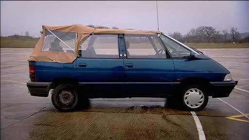 5 Seat Convertible - Does it exist?? - Page 1 - General Gassing - PistonHeads - The image shows an outdoor setting where a small blue car is parked on a tarmac surface. The vehicle has a canopy roof that has been partially rolled down, offering limited shade. The car appears to be a light blue hatchback, with no visible license plate. There's no sign of people in the vehicle or in the surrounding area of the image. The lighting suggests it might be an overcast day, and in the background, there are trees and a patch of grass.