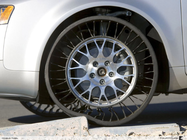 A close up of a motorcycle parked on a street - Pistonheads - The image captures a close-up view of the front wheel of a car. The car appears to be a Jeep, identifiable by its distinctive grille. The front wheel, visible only from the inside, is fitted with what looks like a fuzzy tire tread pattern. The tire and rim are clean, suggesting good maintenance. The car's silver color reflects a bit of the surrounding light, indicating that it might be indoors. There is a small chip in the black asphalt under the tire, close to the curb.