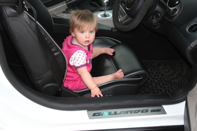 Ferrari California baby seat in rear... - Page 1 - Supercar General - PistonHeads - In the heart of the car's interior, a young child is seated, their small hand placed firmly on the front passenger seat. They are wearing pink, adding a vibrant splash of color to the scene. The car's dashboard, visible in the background, adds depth to the image. The perspective is from the driver's seat, offering an intimate view of the interaction between the child and the vehicle. The child's serious expression stands out, adding a layer of intrigue to this everyday scene.