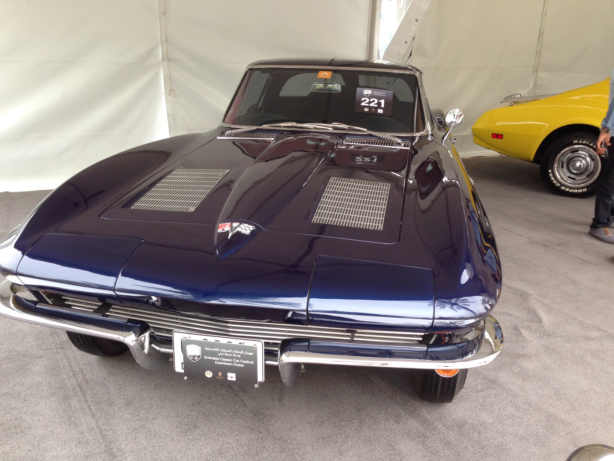 A car is parked in front of a parking meter - Pistonheads - The image captures a vintage black and gold Corvette parked inside a tent. The car's shiny exterior reflects the interior lighting, highlighting its detailed design and the graceful curve of its body. In the background, another classic car showcases a vibrant yellow color. A few people are observing the cars, their focus intent and curious. One individual stands near the tent entrance, perhaps admiring the stunning vehicles or wondering about their histories.