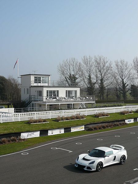 At Goodwood today..... - Page 1 - Goodwood Events - PistonHeads - The image captures a dynamic scene on a race track. In the foreground, a white racing car, part of the Lamborghini racing team based on its livery, is captured in motion, moving quickly towards the right side of the image. The car's sleek design and performance-oriented cues suggest it's amidst a high-speed lap.

The background of the image provides a contrast to the car's pointed orientation: it shows a distinctive, two-story building commonly associated with race track facilities. The structure is predominantly white, with lines of smaller windows along its lower level and a series of larger windows above, hinting at a combined architectural statement and practical necessity for observers and team members.

The building is framed by dense, bare trees, possibly evergreens, which stand stark against the building's white facade. The open sky above reveals a day with clear weather, which suggests favorable conditions for a racing event.

Overall, the image represents a moment of high-speed action against the backdrop of a race track's facilities, evoking the thrill and sophistication associated with professional racing.