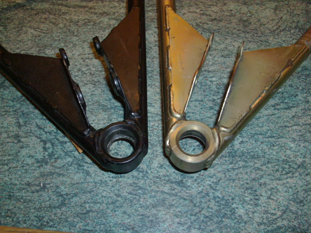 Difference Pistonheads Spot Wishbones - The image presents a vivid contrast of two vehicle parts against a marbled blue-green background. The parts are metallic automotive bumpers, one in a sleek, unpainted black finish and the other with a gold or bronze-like color. Their close proximity and positioning suggest they could be parts of a single vehicle being compared or assembled. The parts appear to be well-crafted, likely made of durable materials like steel or aluminum. The entire image gives an impression of precision workmanship.