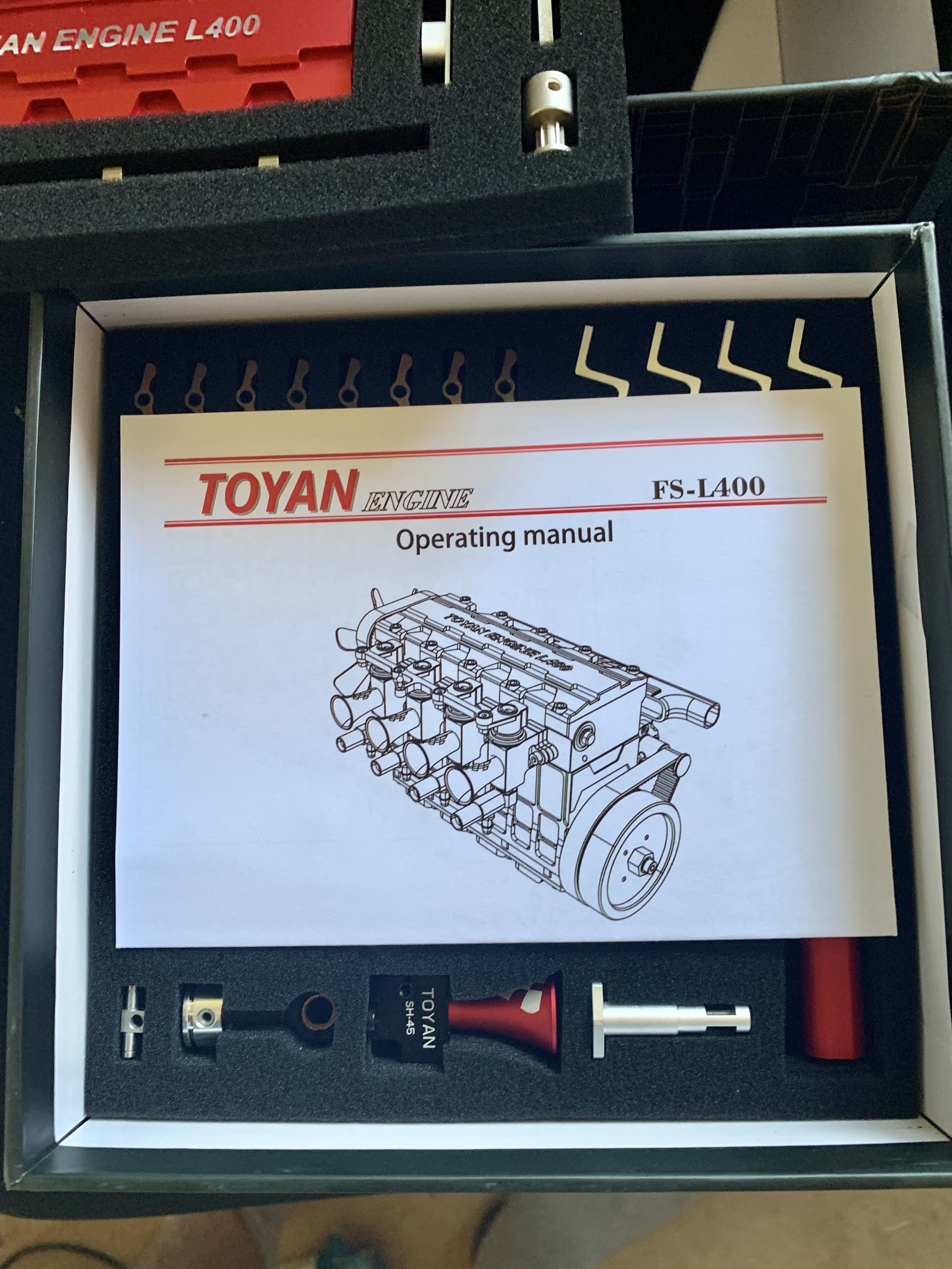 Yet more frivolous purchases, stuff you don't need... - Page 49 - The Lounge - PistonHeads UK - The image presents an open box containing a manual for a toyota engine. The box, which is black and rectangular, contains various tools and equipment required to assemble the model engine. A diagram of the engine parts is visible on a white piece of paper inside the box. The manual appears to be in English, with instructions for the assembly process. This suggests that the box is part of an engine kit or assembly set for a toyota model.