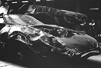 Moment Pistonheads Sir Weve Bit William Mira - The image displays the side profile of a severely damaged car, with its bodywork crumpled and disfigured, suggesting a significant collision. Several dents and creases are clearly visible on the vehicle's exterior. It appears to be positioned indoors, possibly in a service center or garage. The car's body is coated in a smooth gloss, and despite the damage, the reflections from the light source indicate that the vehicle has been actively used or exhibited. The vintage appearance of the car, combined with the character of the black and white photograph, invokes a feeling of nostalgia and the passage of time.