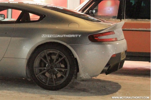 Skirts Vantage Side Bumpers Pistonheads - This image shows a modern, expensive-looking sports car parked alone on the street into the night time. The car is gray with dark wheels and has a sleek design. A distinctive feature of the car is a white logo "MOTORAUTHORITY" on the trunk, which indicates a possible custom or branding. The reflection of the car is visible on the wet street, suggesting that the ground has been recently cleared of snow. In the background, another car is partially visible, hinting at a street likely located in an urban area.