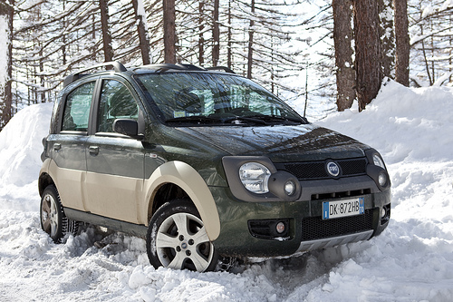 A car is parked on the side of the road - Pistonheads - The image shows a Nissan Serena, a black and tan SUV, parked in a snowy environment. The car is partially covered with snow, indicating recent snowfall. The surrounding landscape is also covered with snow, and it appears to be towards the trees, suggesting a natural, outdoor setting. There is a watermark or text overlay on the vehicle, which is typical for promotional or stock photos. The vehicle looks sturdy and has a robust design, which is fitting for winter conditions.