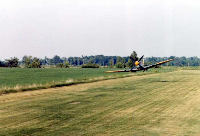 Revival Goodwood Pistonheads - The image depicts an aerial view, capturing a single crop duster aircraft in mid-flight. The plane is clearly the focal point of the image, as it is positioned centrally and occupies a significant portion of the frame. The aircraft appears to be an old-style crop duster, characterized by its sturdy, rectangular body and a set of large propellers.

It's flying over a verdant green field, which might be used for agricultural purposes, given the presence of trees nearby. The field is vibrant, suggesting it's well-maintained.

The plane appears to be approaching some trees from the left, indicating that the aircraft is flying to the right of the image. The trees are spread out in the background, creating an interesting contrast with the open field.

The overall atmosphere of the image is peaceful yet dynamic, capturing a moment of agricultural aviation activity in the midst of a sunny day.