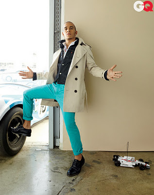 Pistonheads - The image features a man standing in a garage backdrop. He is dressed in a three-piece beige suit, paired with teal trousers, and is holding his hands outstretched. His pose is dynamic, giving a sense of motion and style. A remote control car lies on the ground in front of him. This scene suggests a blend of professional work and personal interests, likely hinting at the man's aspirations in a different context from the one he's currently in.