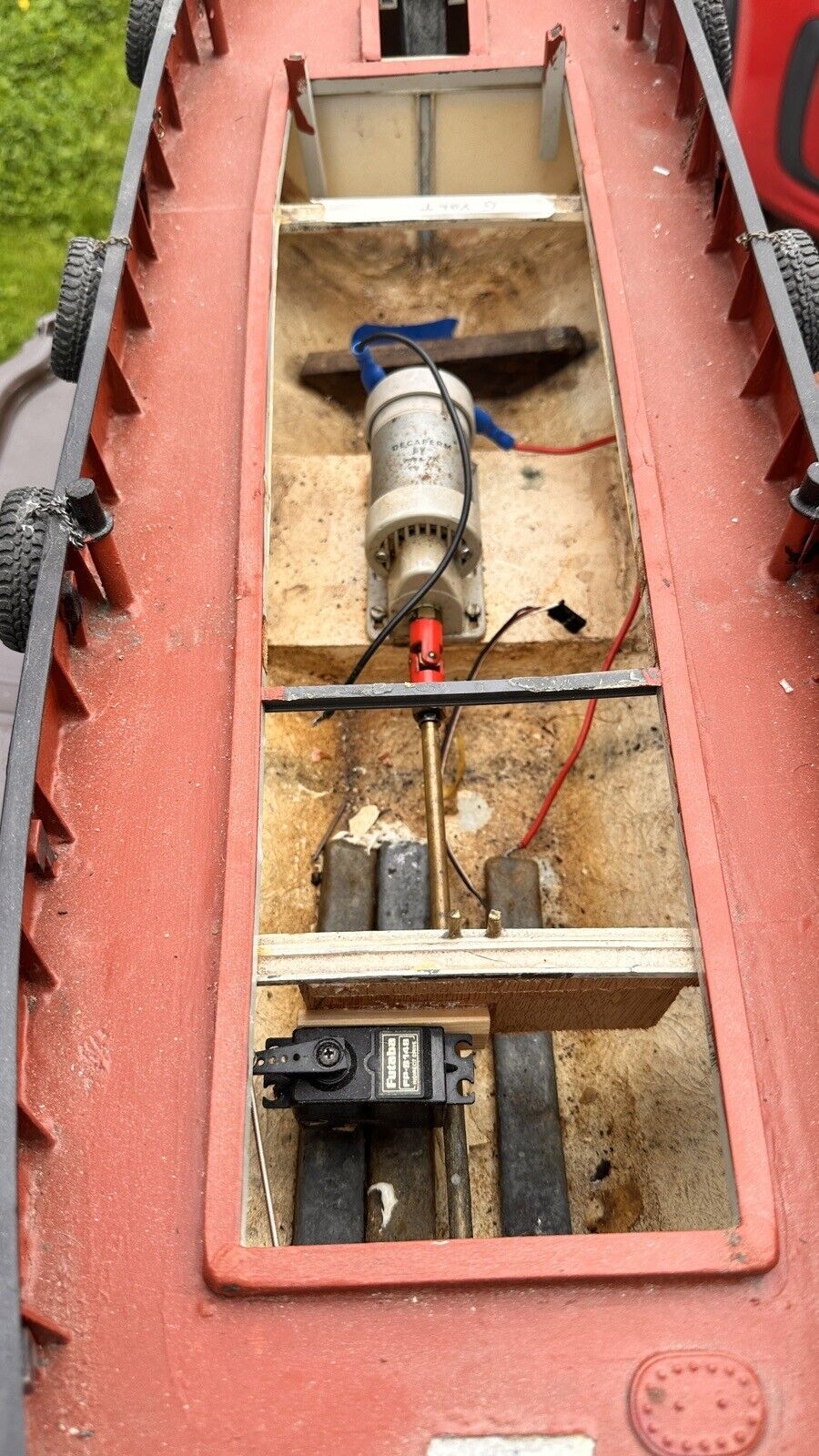 Pistonheads - The image shows a close-up view of the interior of a boat, which appears to be in need of repair or cleaning. There are various tools and equipment inside, including a drill press, suggesting recent work or ongoing maintenance. The boat has an open hatch revealing its contents, and there's a visible connection to an external power source, possibly indicating ongoing repairs. A red object is also present within the boat, but its purpose isn't clear from the image. The boat's interior is well-lit, casting shadows that highlight the internal space. The background of the photo seems to be outdoors, with a glimpse of greenery, hinting at the possibility that this boat may be stored outside when not in use.