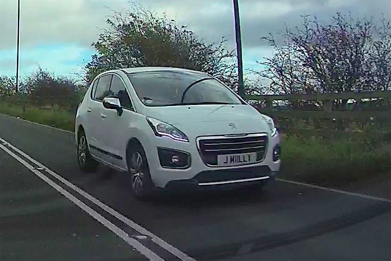 What C124PPY personalised plates have you seen recently? - Page 40 - General Gassing - PistonHeads - The image captures a moment on a rural, two-lane road. A small white car, adorned with a license plate that reads "JMLY", takes center stage, moving along the left side of the road. The car's sleek design suggests it might be a new or modern model. The road itself is speckled with grass and flanked by trees, creating a serene and natural setting. Despite the overcast sky, the high vantage point of the image offers clear visibility of the surroundings. The scene exudes a sense of tranquility and solitude, as if the car is the only sign of life on this peaceful stretch of the road.