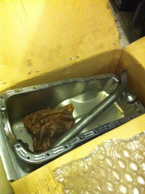 A close up of a toilet in a bath room - Pistonheads - The image shows a large metal appliance, possibly a sink, placed inside a cardboard box. The appliance appears used or discarded, as evidenced by the stains on the surface and the overall condition of the metal. Alongside the sink, there is a pouch made of aluminum foil, possibly intended for insulation or protection during transport or storage. The box seems to be opened slightly, indicating that the items inside are being moved or accessed. The flooring appears to be a light-colored surface, providing a neutral background that contrasts with the metallic appliance and the darker hues of the cardboard box.