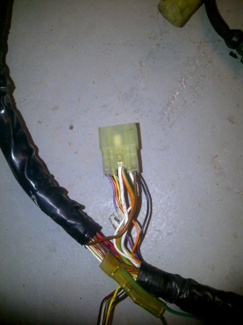 wiring help please, LS install - Page 1 - Major Mods - PistonHeads - The image shows a cable with various colored conductors. A green connector is attached to one end of the cable, and the other end appears to have multiple wires connected to it, all neatly bundled in a black sleeve. The image is taken from a low angle, looking up at the cable, and it's placed on what looks like a cement or concrete surface with visible scratches and marks. The focus of the photograph is on the connectors and wires, with the background being less defined due to the angle and distance from which the picture was taken.