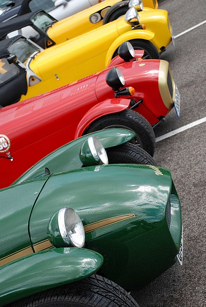 Goodwood Breakfast Club, Pre 1966 classic sunday - Page 1 - Goodwood Events - PistonHeads - The image presents a vibrant scene of a parking lot with row upon row of colorful racing cars. The cars are parked neatly in numbered spaces, exhibiting a variety of colors including red, green, yellow, and black. Their streamlined designs and polished surfaces reflect the light, indicating their readiness for action. The first car in the line appears to be slightly angled towards the foreground, giving a sense of depth and perspective to the image. The surface of the parking lot serves as a neutral backdrop, allowing the vivid colors of the cars to stand out.