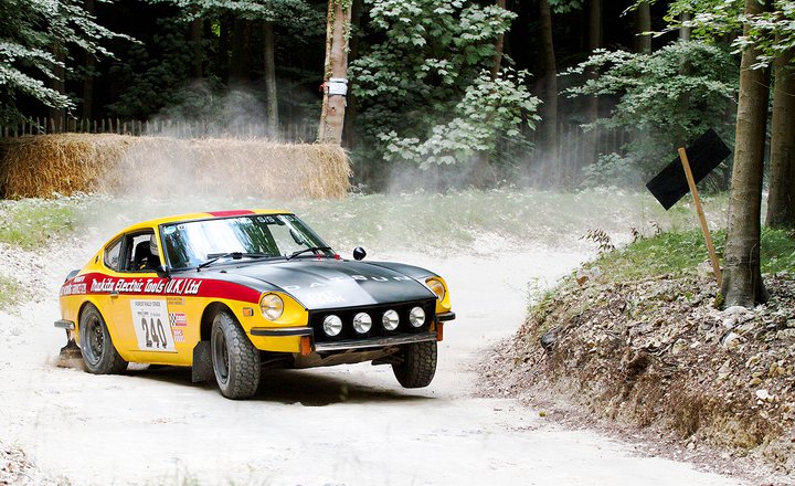 any 240z owners here? - Page 1 - Jap Chat - PistonHeads - In the image, a yellow and red rally car is captured in action, navigating a gravel road amidst a forest. The number 240 is visible on the side of the car, indicating its participation in a rally event. The car is traveling on the left side of the road, and is surrounded by tall trees, suggesting a secluded, possibly rural setting. The sky appears overcast, perhaps hinting at recent or impending rain. The image conveys a sense of adventure and competitive spirit.