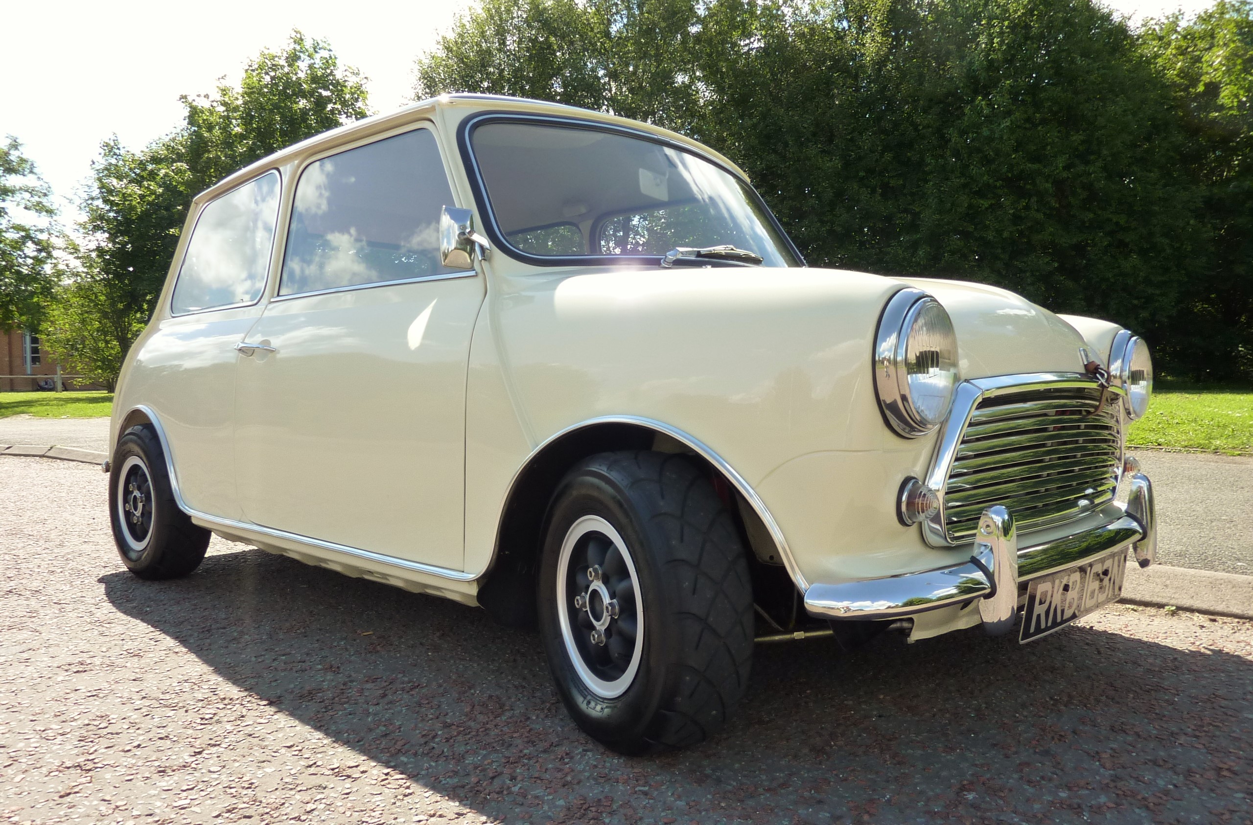 Classic Mini pics - Page 4 - Classic Minis - PistonHeads - The image features a classic, vintage car parked on a gravel driveway. It has a solid white color and a black soft top, giving it a timeless look. The vehicle exhibits distinctive features of an old-fashioned car with round headlights and a unique grill design. The background reveals trees and a clear blue sky, suggesting a pleasant outdoor setting.