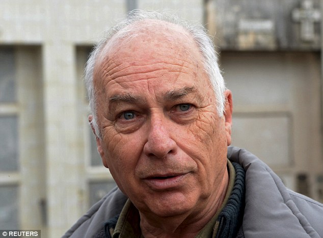 A man in a suit and tie holding a cell phone - Pistonheads - The image shows an older man outdoors. He has neatly combed hair, is wearing a greyish jacket, and his facial expression appears neutral. The setting suggests an urban environment with a building visible in the background. The focus is on the man's face, and he is the main subject of this image.