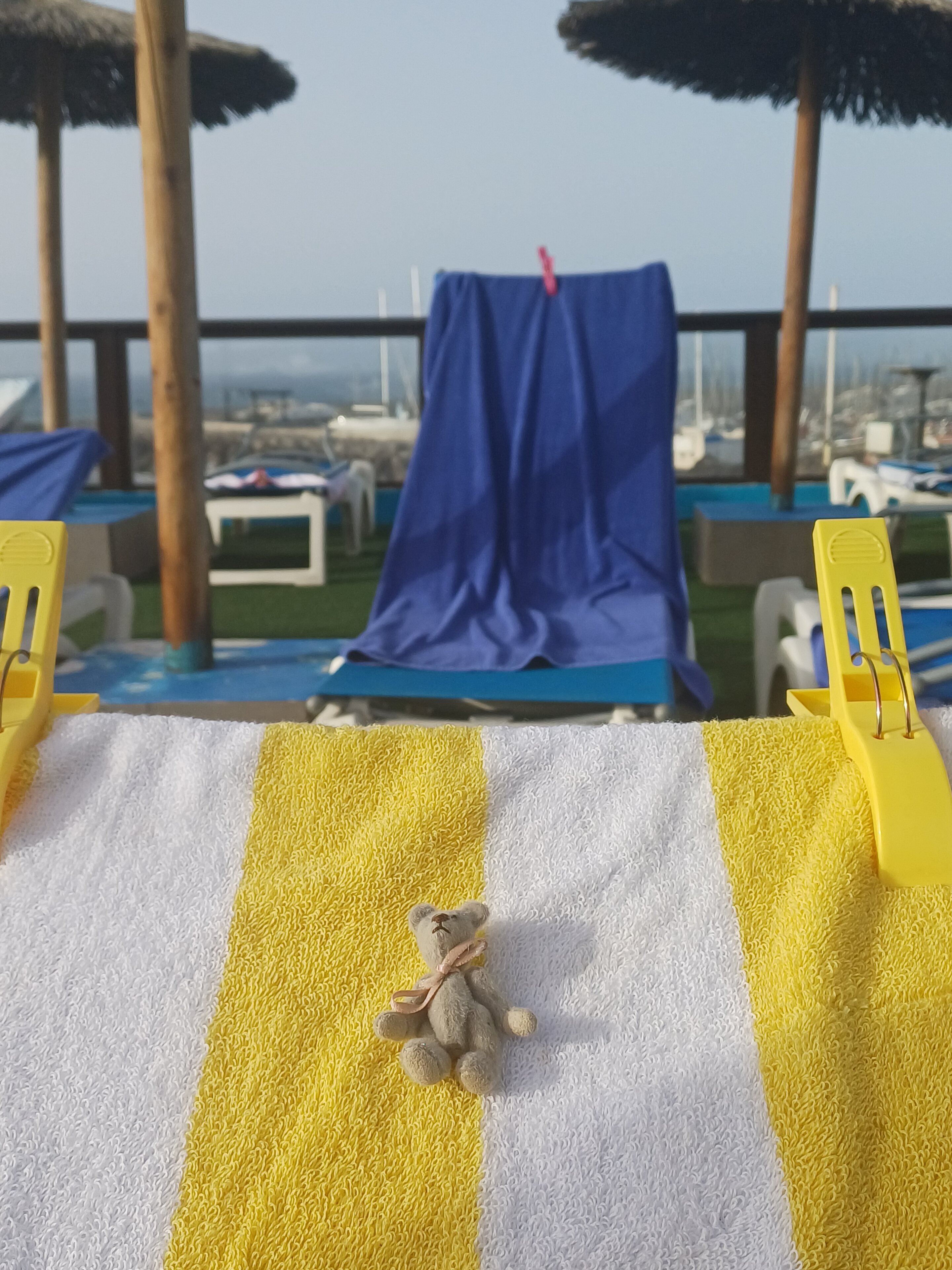 Pistonheads - The image captures a serene beachside setting. There's a lounge chair in the foreground, and a blue towel is spread out on it. A yellow towel is also visible nearby, suggesting a sunbathing or relaxation area. In the background, a swimming pool can be seen, adding to the leisurely atmosphere. Above all this, a light blue sky stretches out, completing the picturesque scene.