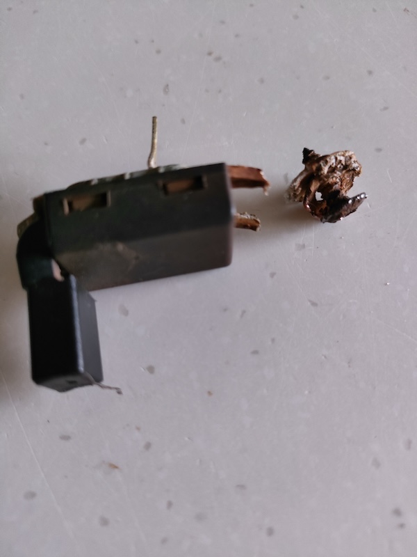 Pistonheads - This image shows a close-up of a small, discarded object on a white surface. It appears to be an electronic device or component, with several visible parts including a battery pack and possibly other circuitry or connectors. The device is placed next to what looks like a small piece of debris or trash, suggesting the item has been left behind or might have fallen out of its original place. There's no text in the image, and the focus is on the object itself rather than any background context.