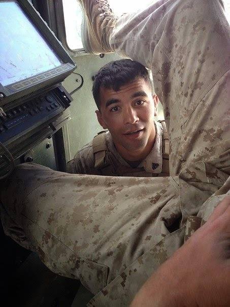 The image captures a moment inside a military vehicle, where a soldier is engaged in conversation. He is dressed in fatigues, complete with the standard issue boots. His pose suggests a casual demeanor despite being in an army setting. The interior of the vehicle reveals the typical features found in such vehicles, including equipment and storage areas.