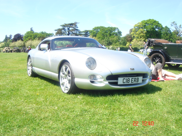 Pistonheads - The image depicts a vintage car, possibly an Alfa Romeo, which features a distinctive grille and a license plate reading "CI18 ERD". The car is parked on a grassy area, suggesting a relaxed, outdoor setting. A few indistinct figures can be seen in the background, but there are no people immediately around the car. The time on the camera is "22 12:40", indicating when the image was captured. The overall mood of the image is serene and nostalgic.