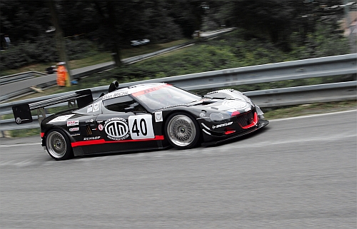 A large white truck driving down a street - Pistonheads - The image portrays a dynamic scene on a race track. The central focus is a sleek, black and red sports car, adorned with the number '40' on its side. The car, featuring aerodynamic accents, is in motion on an asphalt track, rendered in shades of grey, with its tires gripping the tarmac. In the background, a green divider and trees add to the intensity of the scene. The overall composition of the image captures the speed and excitement inherent in auto racing.