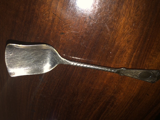 New Teaspoon Advice Please - Page 218 - The Lounge - PistonHeads - The image shows a silver fork with a single tine, placed on a wooden surface. The fork is large and has a metallic sheen. It is the only object in the picture, which creates a sense of isolation. There's no visible text or any other items around it, suggesting a minimalist or simplistic setting. The background is blurred but appears to be an interior space, possibly a room with wooden furniture.