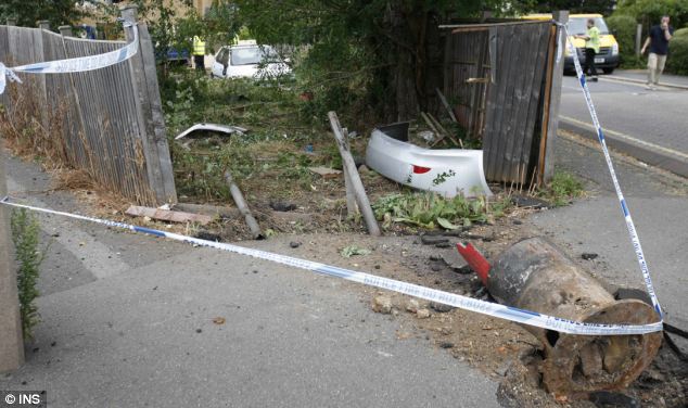 Calculating impact velocity of an accident - Page 1 - Science! - PistonHeads - The image captures a scene of an accident on a small street. There is a white sailboat that has tipped over, its mast and boom scattered around. A police barricade rope crisscrosses the scene, marking off the area. There is a white police van visible in the background. The location appears to be in front of a wooden fence, and there are a few people present, possibly authorities handling the situation.