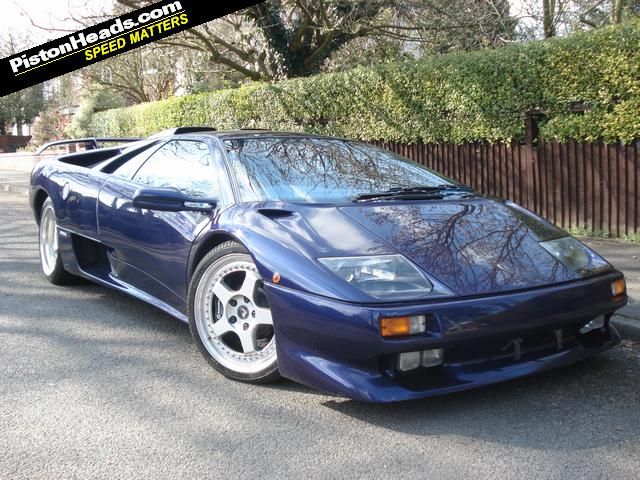 Pistonheads - The image presents a striking blue Lamborghini GT sports car parked on what appears to be a quiet street. The car's sleek lines and aerodynamic design are characteristic of the Lamborghini GT, giving it a powerful and elegant look. The metallic blue color of the car stands out vividly against the urban background, making it the focal point of the image. The car's wheels and red lights add a dynamic touch to its overall appearance. The vibrancy and luxury of the vehicle suggest it could be an expensive and rare model.