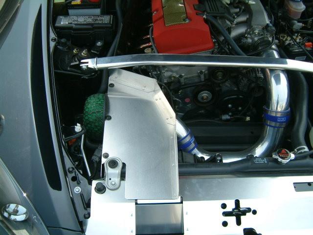 Pistonheads - The image shows an interior view of the engine bay of a car. There is a liquid or oil residing in the engine bay, as well as a prominent red air intake component. A mechanical part with a handle is visible, which might be a part of the vehicle's lubrication or cooling system. The engine appears to be of a high-performance nature, as indicated by the silvery, complex components and the central positioning of the air intake.