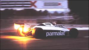 A large truck driving down a street next to a traffic light - Pistonheads - The image is a dynamic action shot of a Formula One car in motion on a racetrack. The vehicle is predominantly white with black text and accents. The track appears to be at night or in a shaded area, giving a dramatic effect to the glow of the flames and the light sources in the background, suggesting high-speed activity.