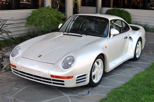 The 2014 Yorkshire Spotted Thread - Page 6 - Yorkshire - PistonHeads - The image features a white Porsche sports car that appears to be of vintage or classic design. It's parked outdoors, with the vehicle's bodywork reflecting some light, suggesting it's a sunny day. The background includes a landscaped area with grass and rocks, and a structure with walls and the top of a column partially visible. There is no visible text or branding on the car in this angle, and the steering wheel is visible through the car's glass panel. The perspective seems to be a low angle shot, likely taken to emphasize the car's design and styling.