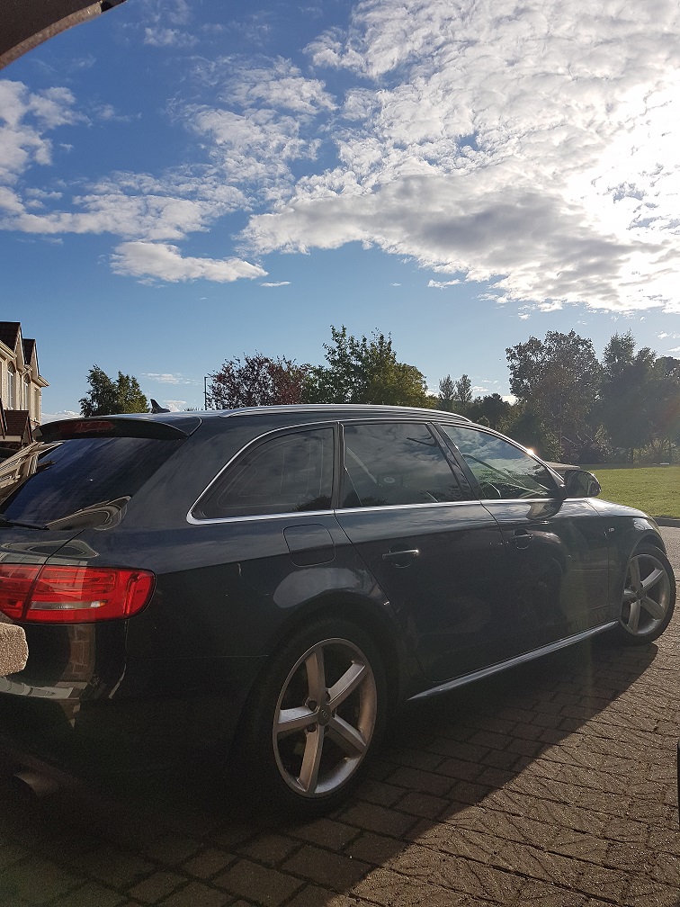 Show us your Audi! - Page 15 - Audi, VW, Seat & Skoda - PistonHeads - The image is an outdoor photograph taken during the day under a clear sky with clouds. It shows a black-colored station wagon parked on a paved surface, with a brake light visible on the left side of the vehicle. The setting near the vehicle appears to be a residential area, with another car and part of a house visible in the background. The lighting suggests the photo was taken in daylight.