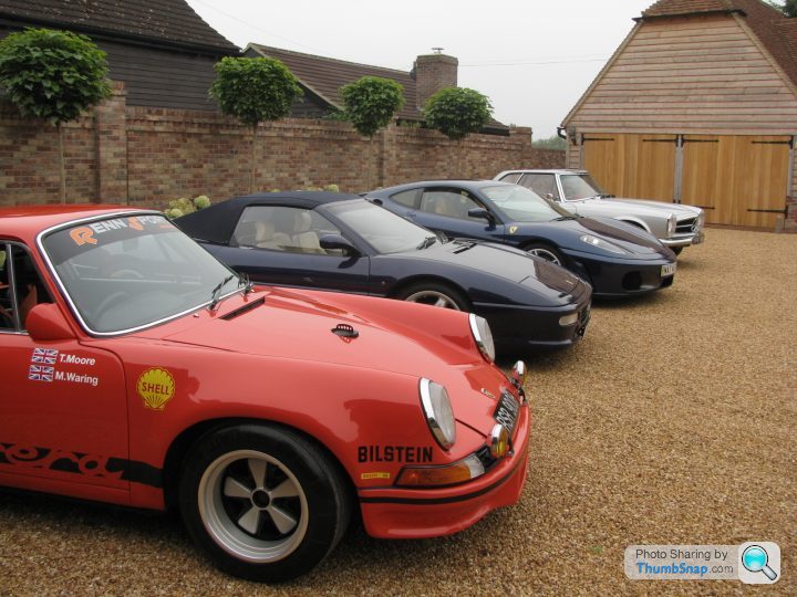 Your Favourite Porsche Pictures! - Page 7 - Porsche General - PistonHeads - This image showcases a vintage vehicle collection parked on a gravel driveway. There are four cars in total, three of which are shades of black or dark blue. The most striking car is a vibrant red vehicle on the left, labeled with white text. The first car in line, this one is well-maintained with a visible coat of polish. The setting seems serene, with a house in the background. The cars are arranged in a straight line, suggesting they are parked intentionally. The image captures the essence of car enthusiasts' pride in their vehicles and their attention to detail, demonstrated by the cars' pristine condition and immaculate parking.