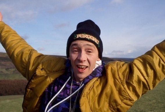 Driving is awful these days, isn't it? - Page 1 - Advanced Driving - PistonHeads - The image captures a young man joyfully expressing his excitement at an outdoor setting with a cloudy sky. He's wearing a bright yellow jacket and a black beanie with the word "CHOG," likely referring to a well-known flower brand, suggesting he might be a fan or an employee. His arms are raised in a triumphant gesture, further emphasizing his enthusiasm.