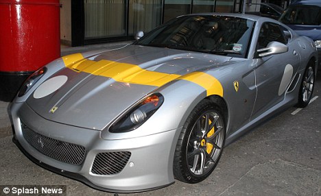 Silver, yellow stripe - Page 1 - Elise/Exige/Europa/340R - PistonHeads - The image features a stately silver sports car with a vibrant yellow stripe accenting its sleek design. It's parked on a city street surrounded by other vehicles, suggesting an urban setting. The car's large alloy wheels and aerodynamic lines hint at its powerful performance. The interior of the car can be seen, where a driver's seat is visible, indicating the car is ready for a trip or a test drive.