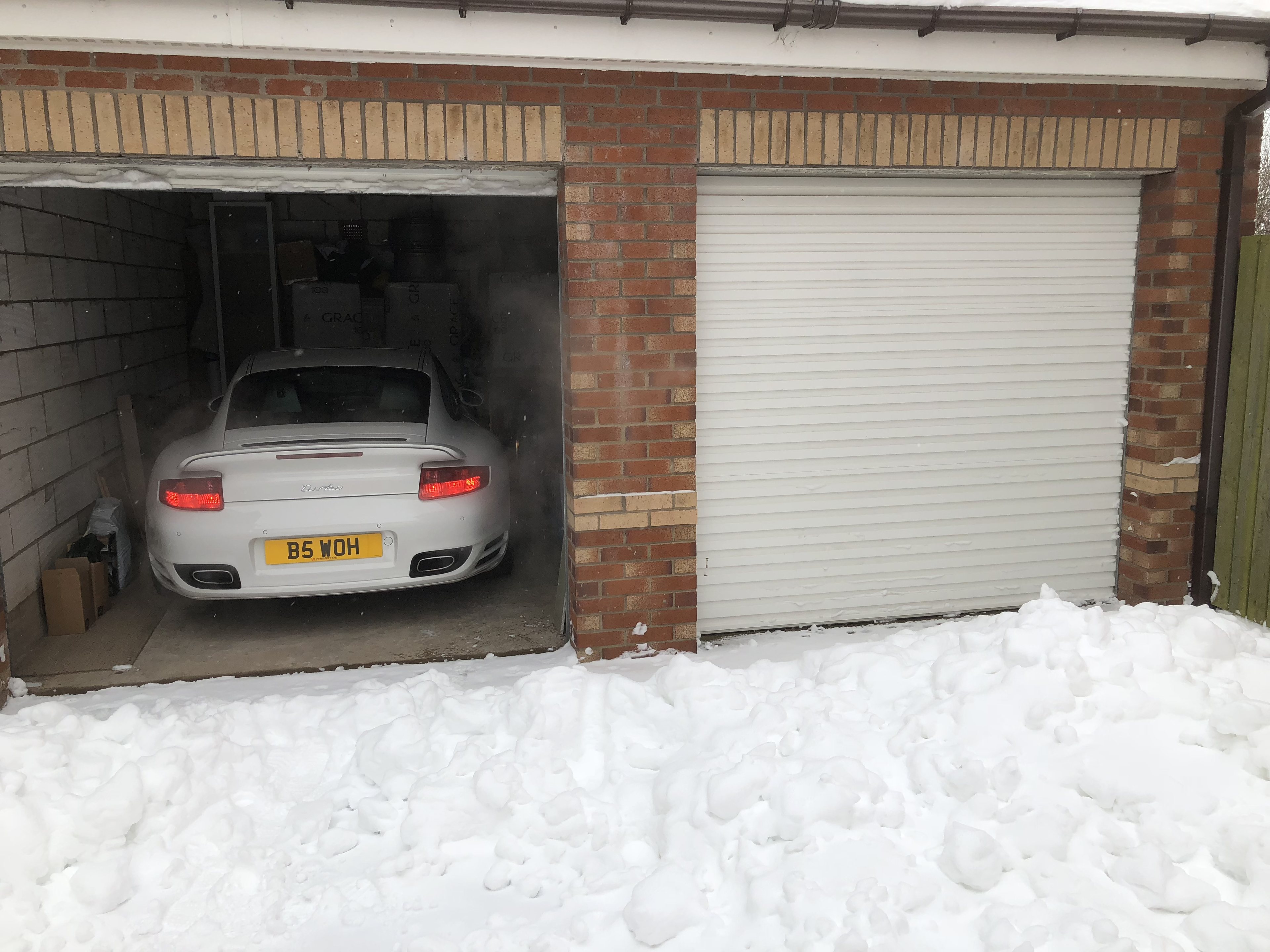 The 997 Appreciation Thread - Page 51 - 911/Carrera GT - PistonHeads UK - The image shows a garage with its door open. Inside the garage, there is a car parked, and the car appears to be in good condition. On the ground outside the garage, there is a significant amount of snow accumulated, indicating that it has been snowing recently or has been snowing for some time. The ground outside the garage looks wet, possibly from recent melting or ongoing snowfall. There is no visible text or distinctive markings on any of the objects in the image to provide additional context.