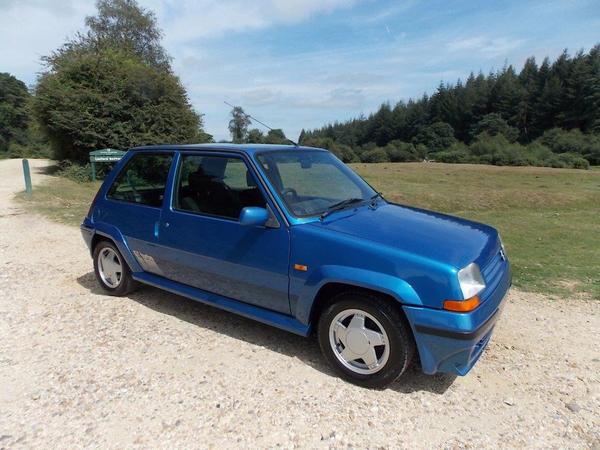 Which attainable car from your youth would you still like? - Page 1 - Classic Cars and Yesterday's Heroes - PistonHeads UK - This image showcases a blue compact car parked on a gravel road. The vehicle appears to be in good condition with the engine compartment slightly open. There's no visible text or branding that can be discerned from this angle. The car is positioned against a backdrop of trees and grass, indicating a rural setting. The sky above suggests it might be early evening or late afternoon, adding a serene atmosphere to the scene.