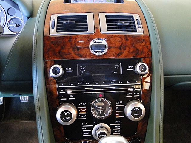 Damn that Tony Hall !! - Page 1 - Aston Martin - PistonHeads - This image showcases the interior of a vehicle, specifically focusing on the dashboard. The dashboard is brown wood with a sleek silver design around the dials and gauges. Various controls and gauges are present, indicative of the driver's side. The color of the controls, including a clock, adds to the sleek aesthetic of the vehicle. The lighting in the car casts subtle reflections on the surface of the dashboard and controls. The image effectively captures the essence of luxury and modern design in the car's interior.