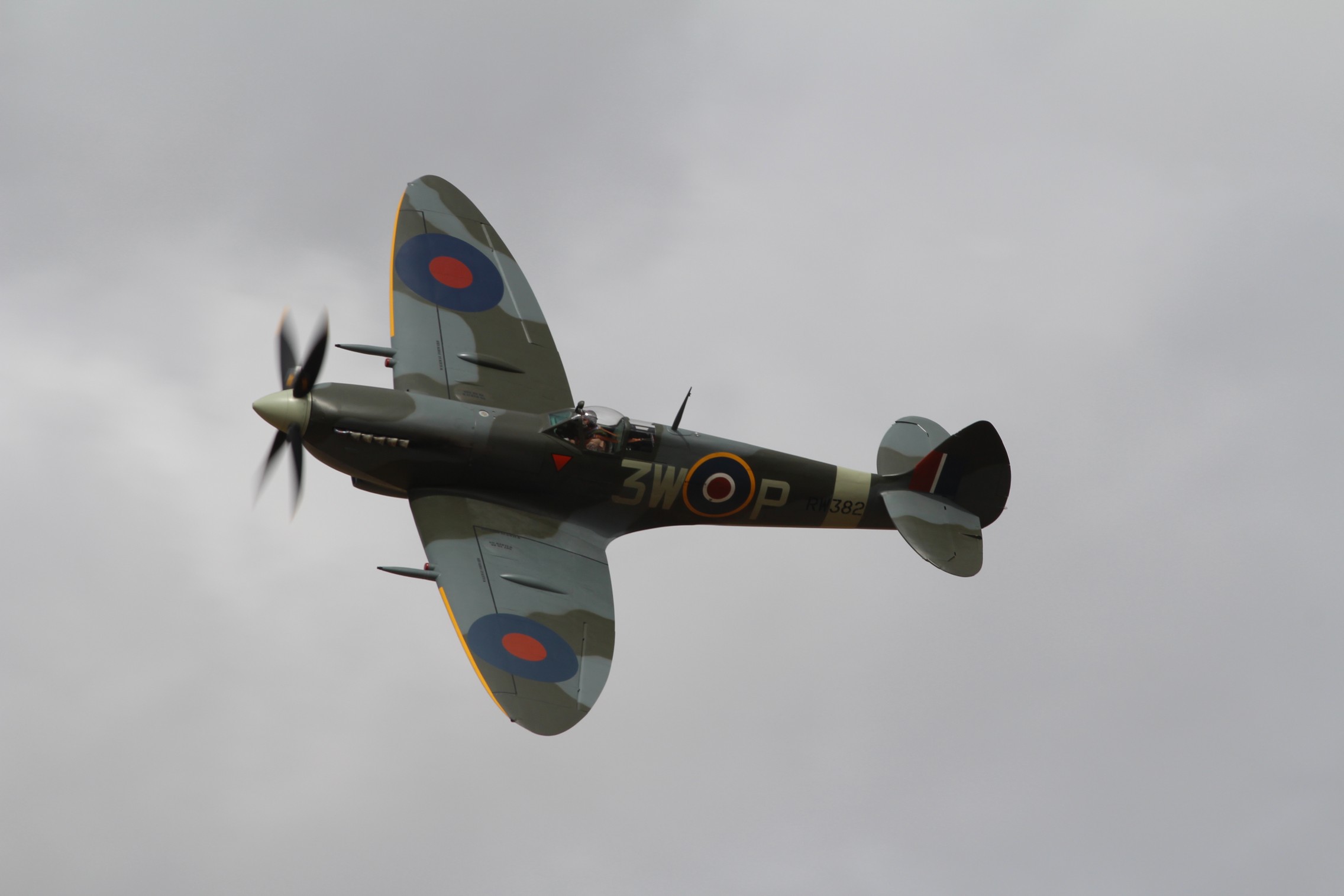 Post amazingly cool pictures of aircraft (Volume 2) - Page 200 - Boats, Planes & Trains - PistonHeads - The image features a camouflaged military aircraft, likely a stunt plane, with a distinctive paint scheme including irregular shapes and stripes. The plane is shot at an angle, as it flies against a gray, overcast sky. It bears the markings 3 in a circle, which is likely its identification number. The propeller is spinning rapidly, and the aircraft appears to be in mid-flight, possibly performing a maneuver or preparing for such.