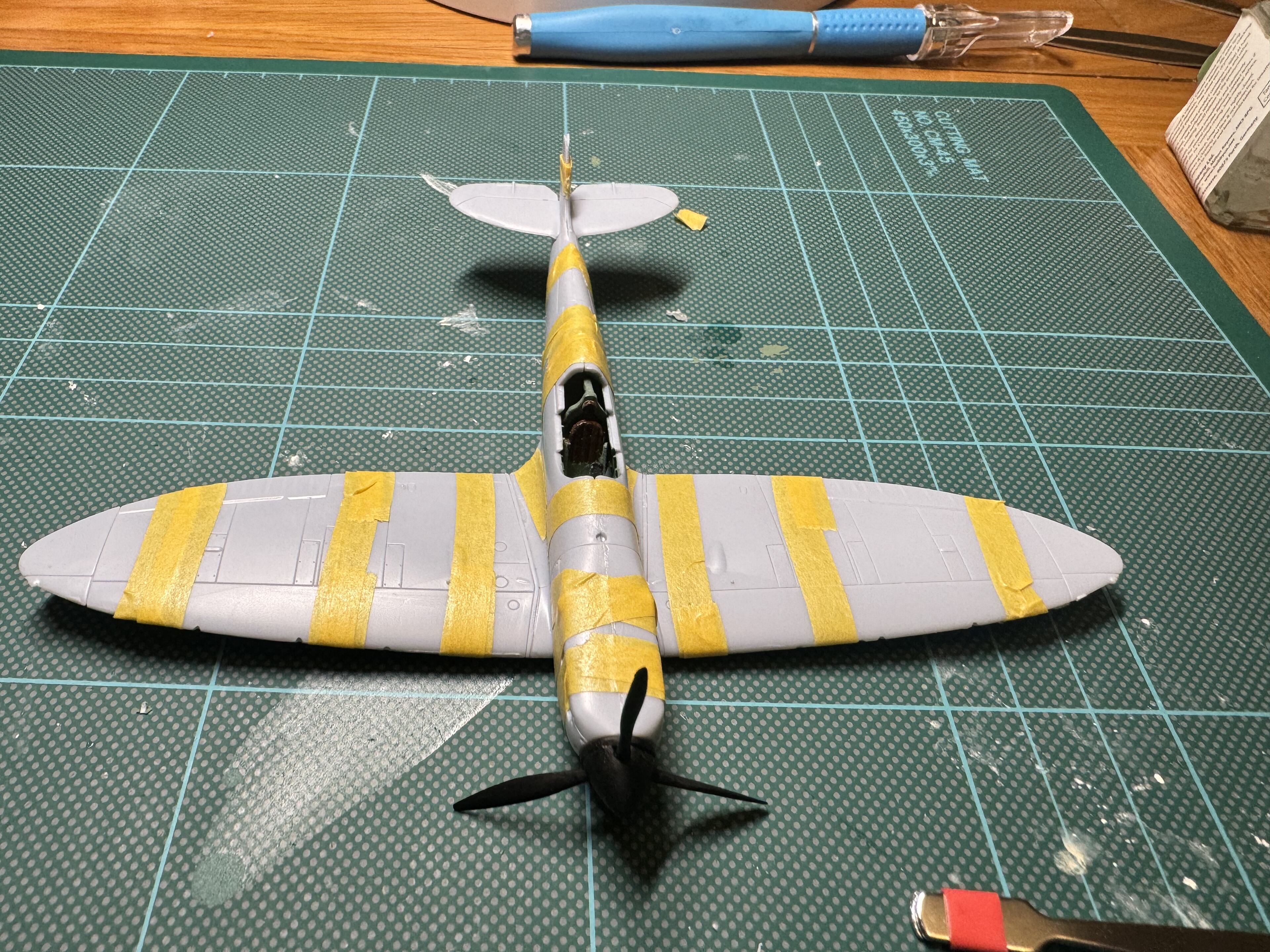Pistonheads - The image shows a model airplane on a workbench, with tools and equipment scattered around. The airplane is painted in the colors of the British RAF, featuring yellow stripes and camouflage patterns. The workbench itself appears to be made of wood and has some tools on it. There are also various materials and parts visible, suggesting that this could be a work-in-progress or an assembly area for model aircraft.