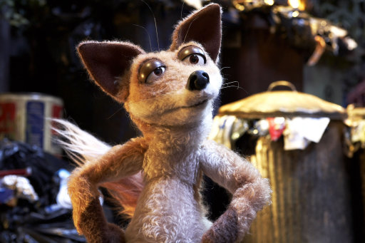 Pistonheads - The image showcases a stuffed fox doll standing upright. The fox is brown with large, fluffy ears and a defined snout. It appears to have brown eyes with black pupils and stitched whiskers. The fox is set against a blurry background that suggests a cluttered room or outdoor setting, but specific details are not clear due to the blur. There are no texts on the image. The positioning of the fox gives it a lifelike and curious stance, as if posed by a photographer. The lighting highlights the detailed stitching used to create the doll, especially around the nose.