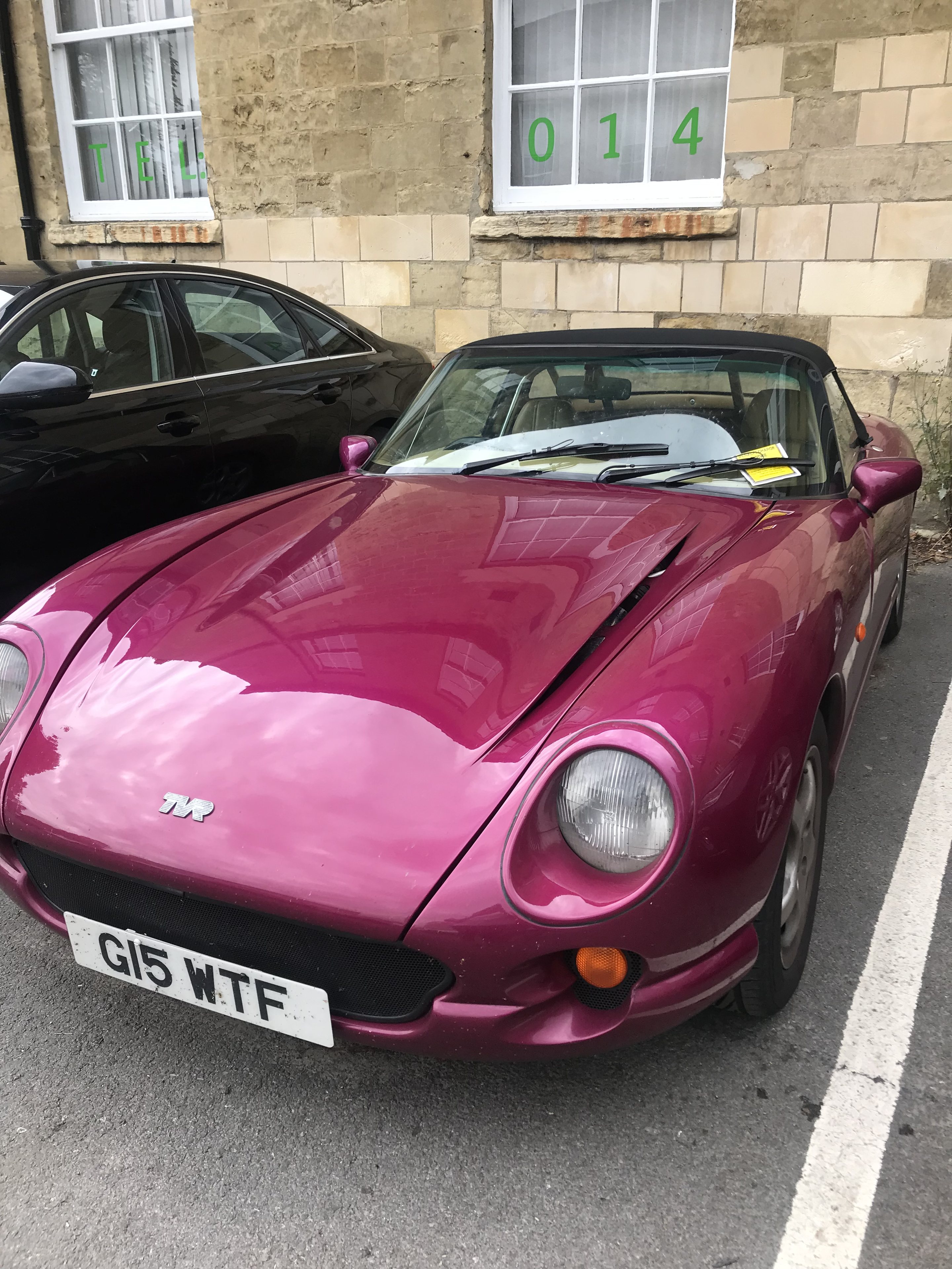 Yorkshire Spotted Thread - Page 161 - Yorkshire - PistonHeads UK - This is a photograph of an eye-catching pink car parked in a parking lot. The vehicle appears to be a sports or luxury model, indicated by its sleek design and distinctive shape. It's positioned at an angle relative to the camera, showcasing its side profile and a portion of its front hood. There are no visible license plates, and the surrounding area includes another parked car behind it and what looks like a building with windows in the background. The overall image has a candid, unposed quality to it.