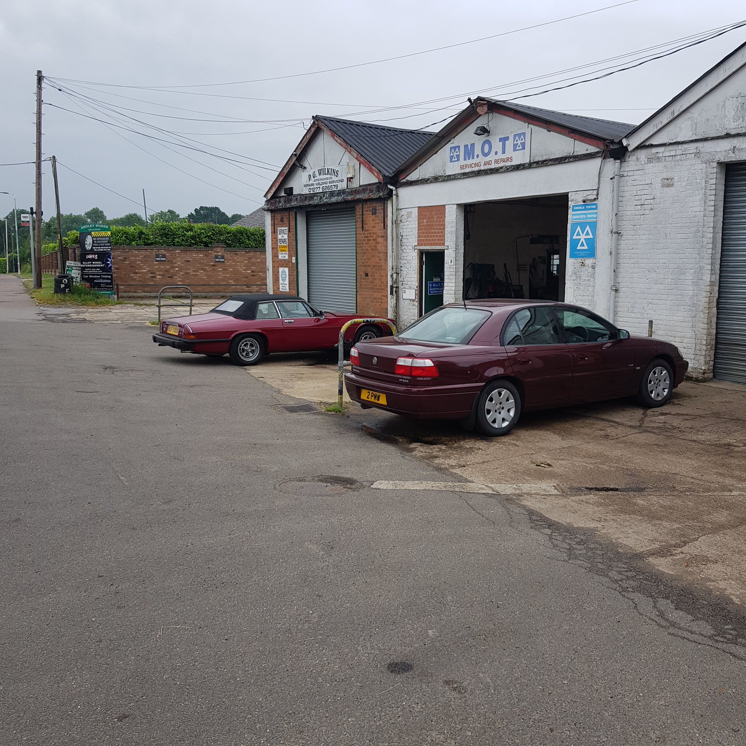 The Kent & Essex Spotted Thread! - Page 409 - Kent & Essex - PistonHeads UK - The image shows an outdoor scene with two cars parked next to each other. They are parked in front of a white building that appears to be a garage or storage facility, as indicated by the presence of a door and what looks like shelving units visible through the windows. On the top left corner of the image, there is text that reads "CAR SALE" with an arrow pointing downwards. The sky is overcast, and it seems to be raining or about to rain.