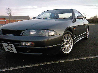 Pistonheads - The image shows a black two-door vehicle. In the upper portion of the image, we can see the sky above and the car's windshield. On the car, there are visible storage compartments on the sides near the rear wheel. The license plate is at the front and features the letters "LA3" indicating the car's registration. The vehicle is parked on what appears to be an asphalt surface with a painted white line. The overall style of the image is casual, with a focus on the vehicle.